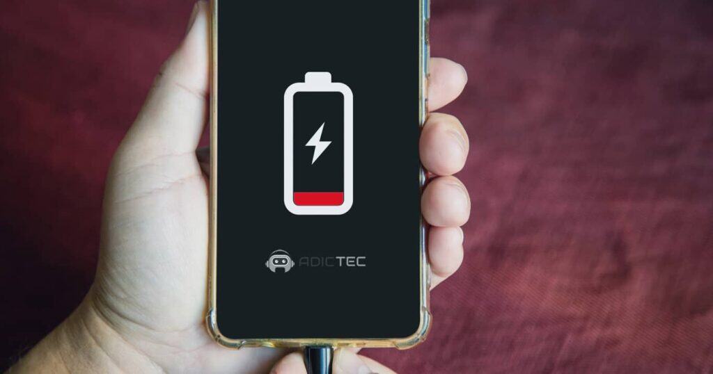 Primer plano de un smartphone con batería baja en pantalla, conectado al cargador para solucionar por qué se descarga rápido.