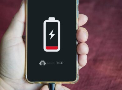 Primer plano de un smartphone con batería baja en pantalla, conectado al cargador para solucionar por qué se descarga rápido.