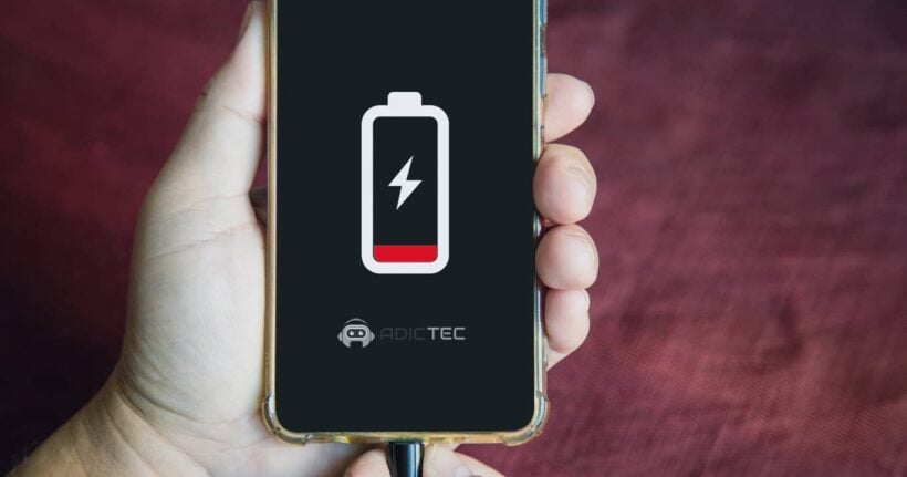 Primer plano de un smartphone con batería baja en pantalla, conectado al cargador para solucionar por qué se descarga rápido.