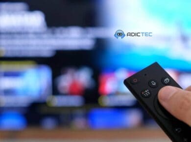 Mano sosteniendo un control remoto de TV frente a una pantalla desenfocada, simbolizando la elección de tu TV ideal entre QNED, QLED y OLED.