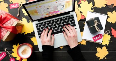 Persona comprando en su laptop ofertas de computadoras para el Buen Fin 2025, con regalos y café en un escritorio decorado.