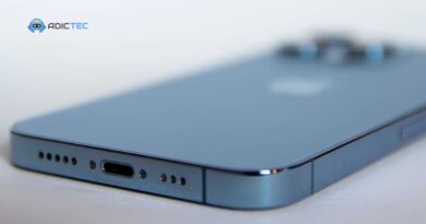 Rejillas del altavoz inferior de un iPhone azul junto al puerto de carga, la zona a limpiar del altavoz del iPhone