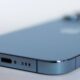 Rejillas del altavoz inferior de un iPhone azul junto al puerto de carga, la zona a limpiar del altavoz del iPhone