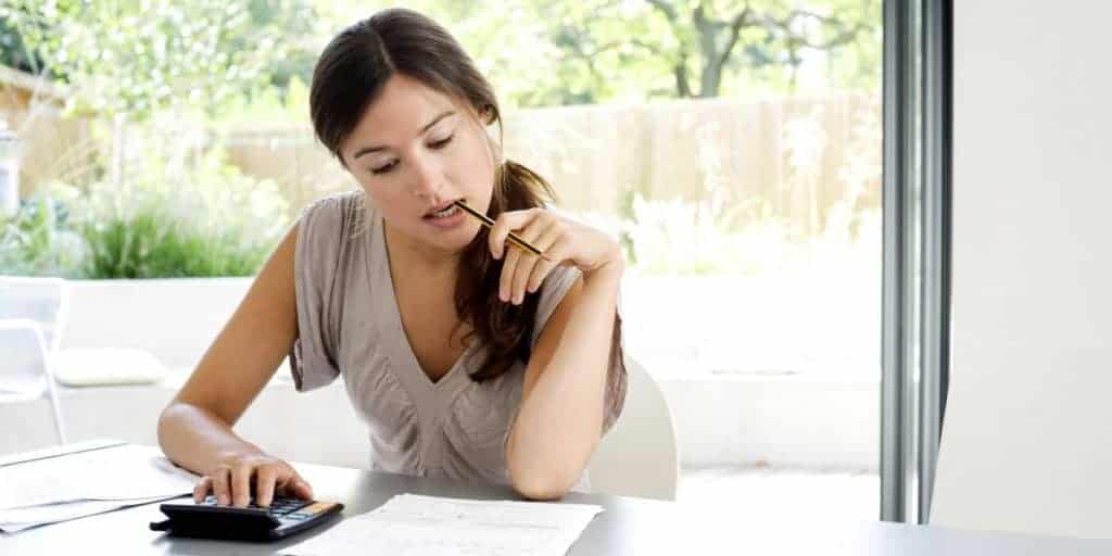 Woman working on a desk while biting a pencil.