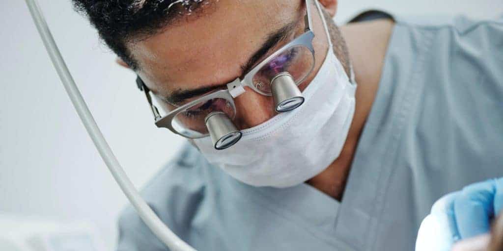 Dentist wearing dental magnifying glasses while doing treatment.