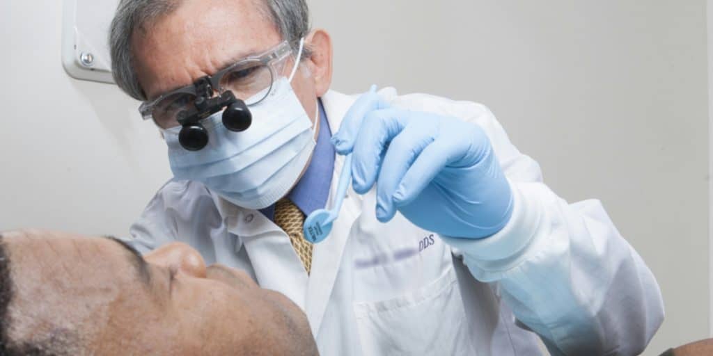 Dentist with surgical mask doing a dental procedure a patient.