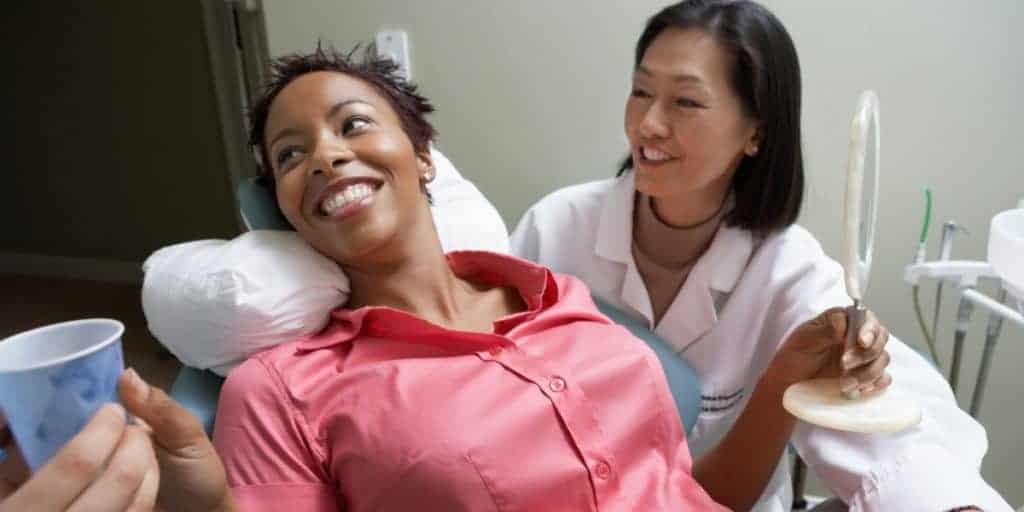 Woman assisted by dentist during dental exam.