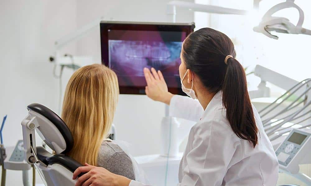 Dentist showing a digital X-ray result for full mouth restoration.