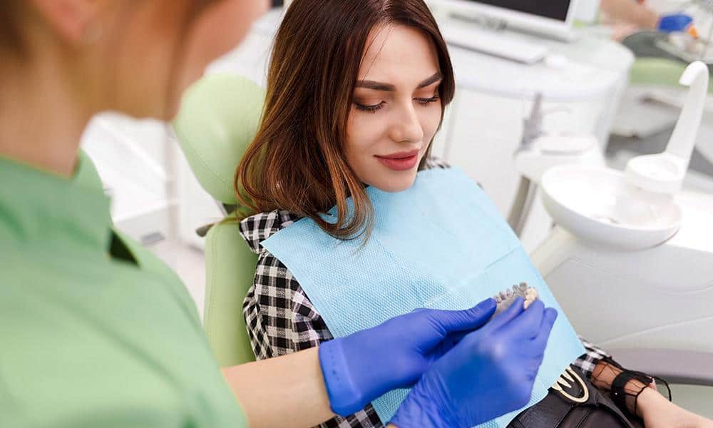 Dental professional showing porcelain inlays to female patient.