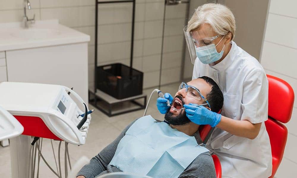 Dental professional cleaning patient's teeth for porcelain onlays.