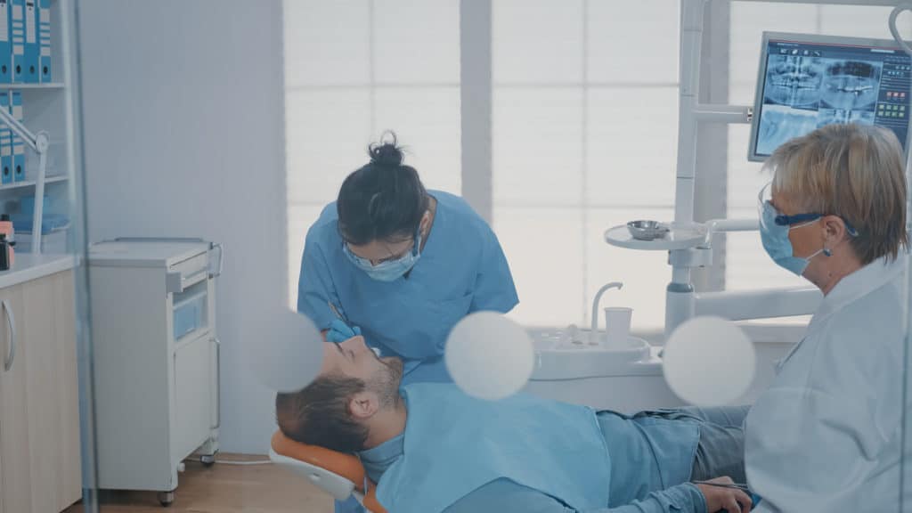 Team of dental experts extracting a tooth at oral care clinic.