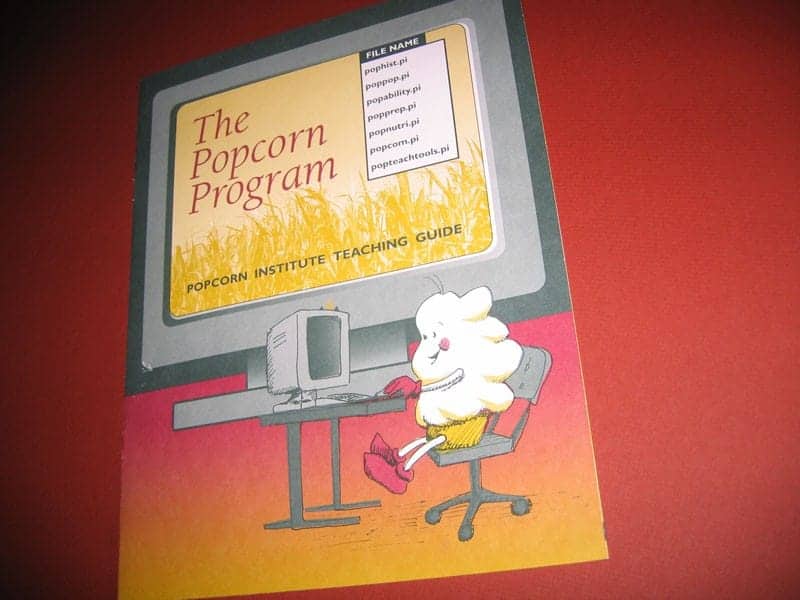 Cover of brochure for the Popcorn Institute featuring Poppy character at the computer.