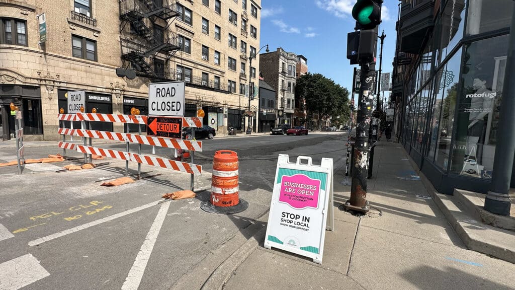 Road closed barricades and a 'Businesses Are Open' sandwich board sign on Lincoln Avenue in Lincoln Park, Chicago, during a street construction closure.