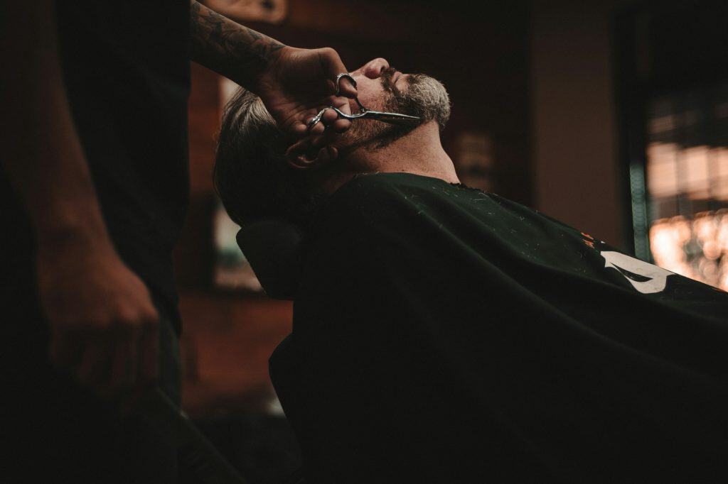 Barber trimming a man's beard with scissors