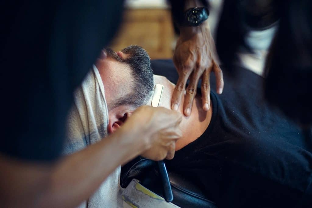 Barber shaving a man's neck with a straight razor
