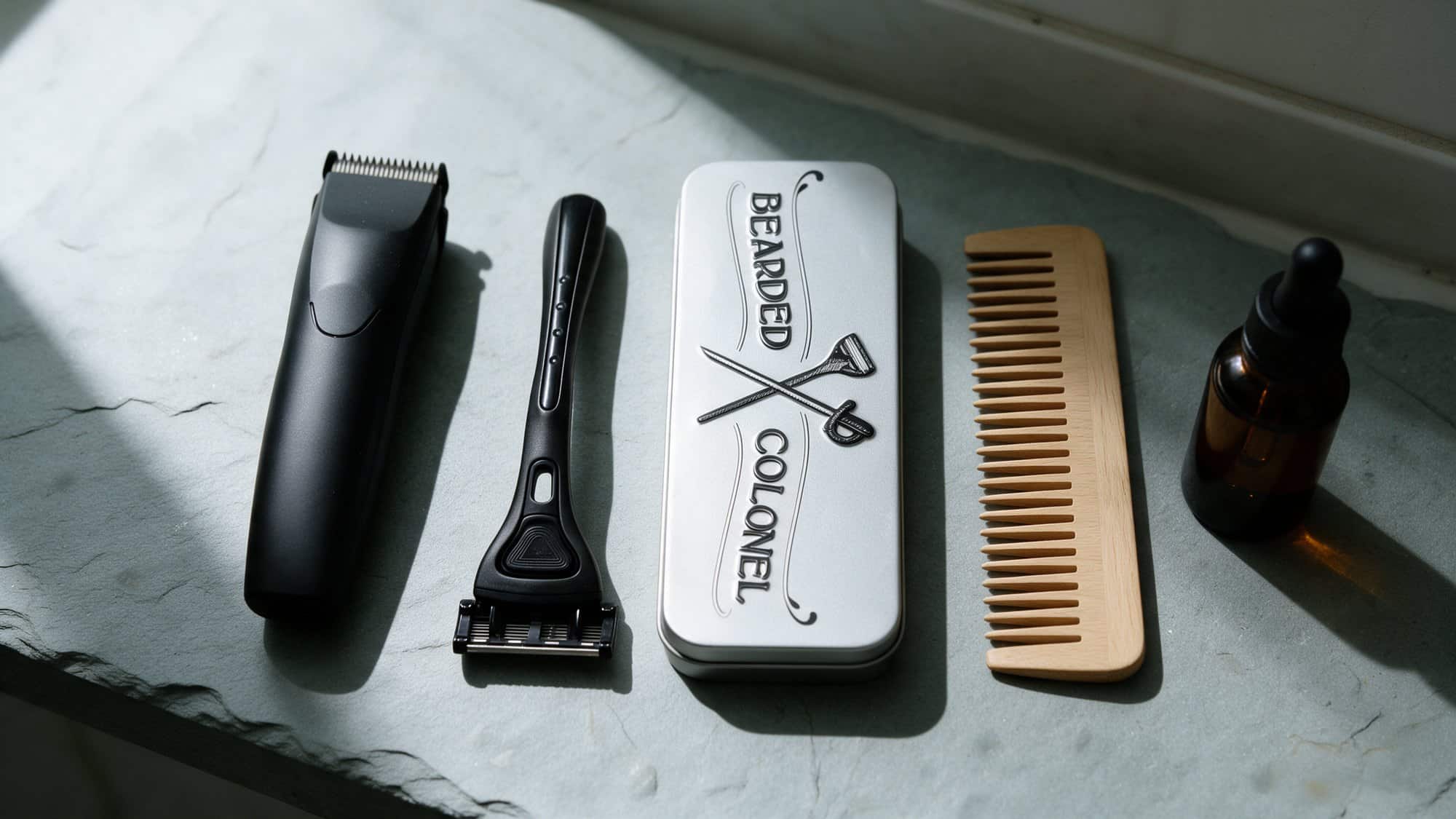 Beard trimmer, Bearded Colonel razor, storage tin of five-blade heads, wooden comb and beard oil on a slate shelf