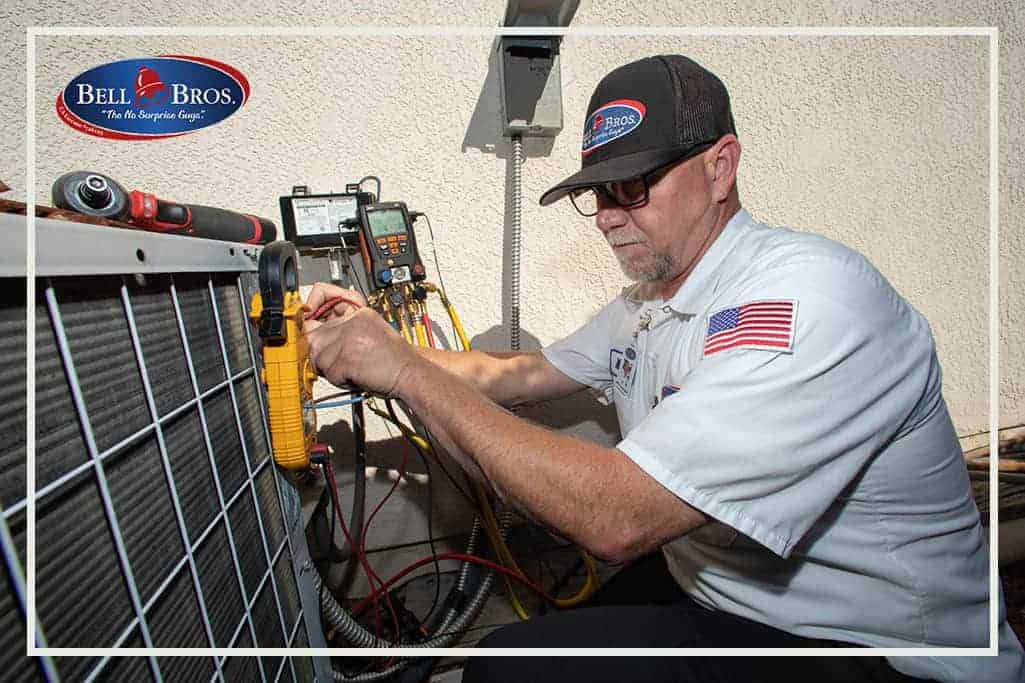 A trusted Bell Brothers technician, clearly identifiable in a Bell Bros. uniform, carefully inspects an outdoor HVAC unit using professional measuring tools and equipment. The prominent Bell Bros. logo appears in the top left corner, highlighting their strong reputation throughout Northern California communities. This scene represents Bell Brothers’ commitment to their No Surprise Guarantee, with background-checked technicians and upfront pricing you can count on.