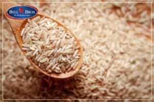 A close-up of a wooden spoon heaped with uncooked brown rice, resting on a generous pile of rice. Just like every Bell Brothers service call—trusted across Northern California—there are no surprises here: our background-checked technicians deliver upfront pricing and the peace of mind guaranteed by our No Surprise Guarantee.