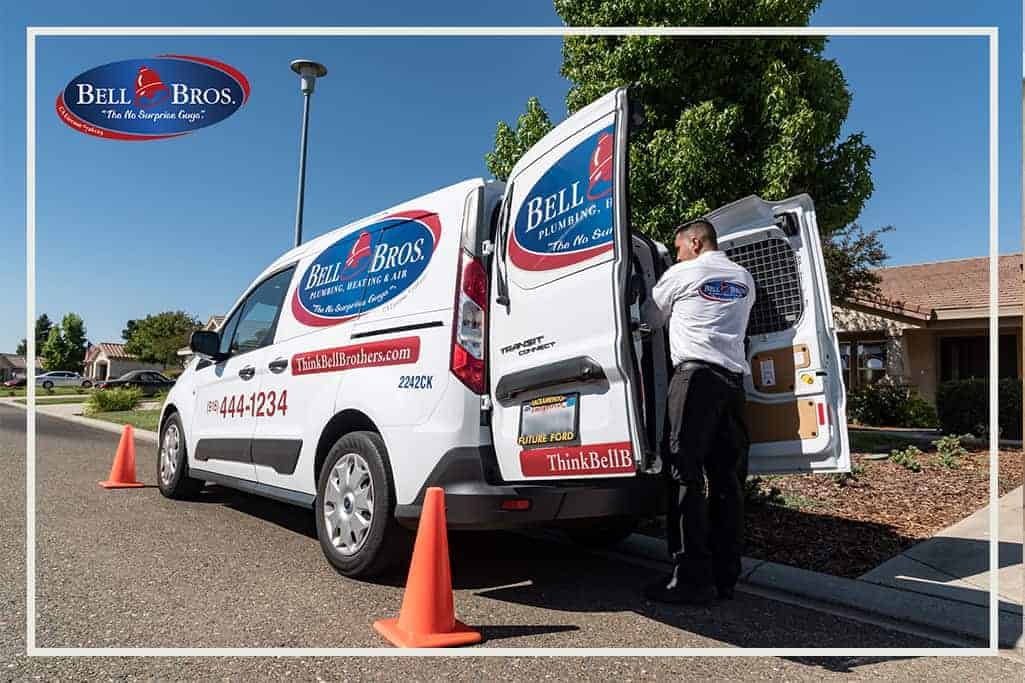 A Bell Brothers Plumbing, Heating & Air service van is parked on a residential street with its rear doors open, ready for expert service. A friendly, background-checked Bell Brothers technician stands by the van, while two orange cones ensure safety in the work area. Known across Northern California communities for our strong reputation, we proudly offer upfront pricing and our No Surprise Guarantee—so you always know what to expect from your trusted home comfort team.