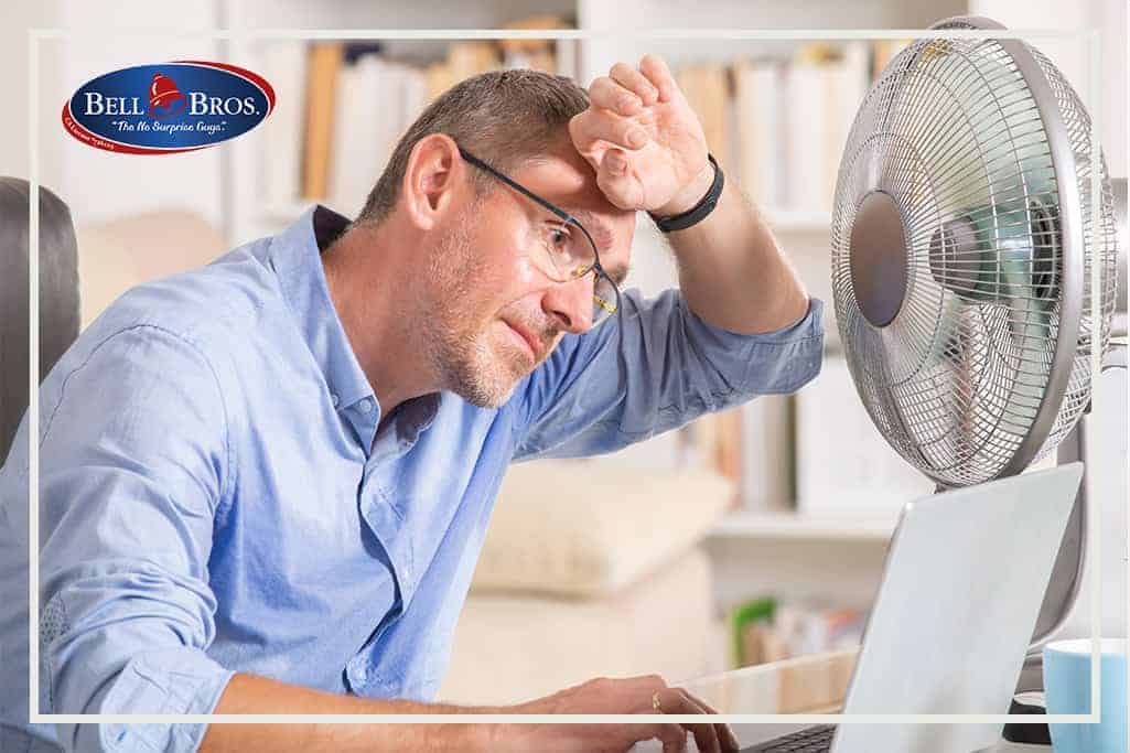 A man sits at his desk, using a laptop and wiping sweat from his forehead as he tries to cool off with a fan—a common sign that it’s time for expert help. With Bell Brothers’ trusted service, you’ll enjoy our No Surprise Guarantee, upfront pricing, and background-checked technicians. It’s the peace of mind that Northern California families have relied on for years!.
