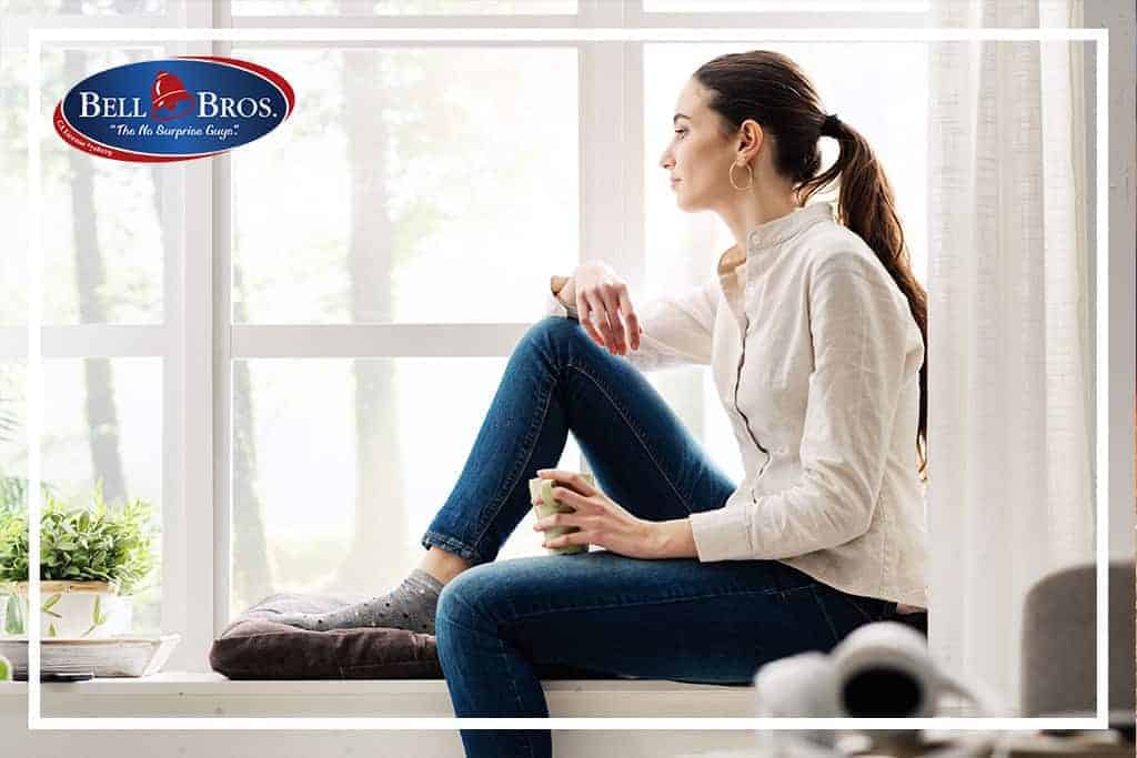 A woman relaxes on a windowsill with a warm mug, enjoying peace of mind thanks to Bell Brothers’ trusted service. The Bell Bros. logo in the corner reflects their No Surprise Guarantee, background-checked technicians, and upfront pricing—qualities that have earned them a strong reputation across Northern California communities.