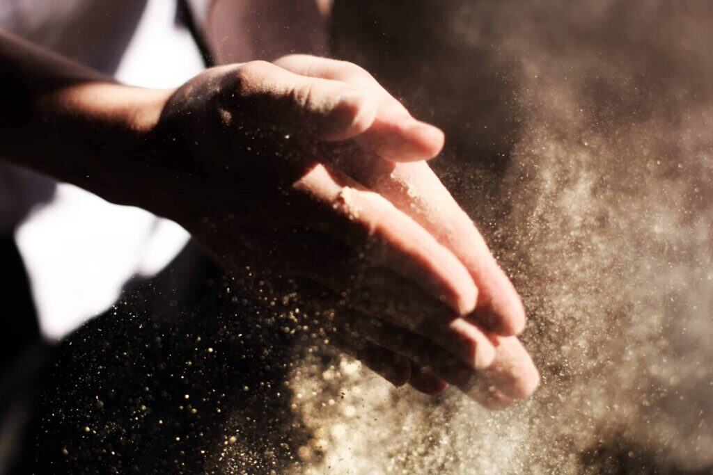 A close-up of hands clapping, releasing a burst of fine dust in the light—symbolizing Bell Brothers’ trusted, upfront approach to service. Our carefully background-checked technicians deliver expert care across Northern California communities, backed by our No Surprise Guarantee and clear pricing every time.