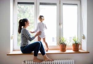A woman and her child enjoy a peaceful moment by the window, surrounded by thriving potted plants—a reflection of the comfort and trust Bell Brothers brings to homes across Northern California. With our No Surprise Guarantee, thoroughly background-checked technicians, and upfront pricing, families just like yours count on our reputable service for total peace of mind.