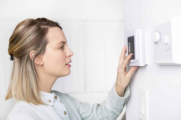 A friendly Bell Brothers technician assists a customer adjusting her digital thermostat in a bright, comfortable home. With our No Surprise Guarantee, clear upfront pricing, and thoroughly background-checked professionals, Northern California families trust Bell Brothers for reliable service and peace of mind.