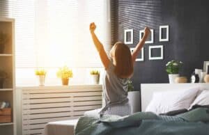 A woman enjoys a peaceful morning, stretching in her sunlit, modern bedroom filled with vibrant plants and family photos—a reminder of how Bell Brothers’ trusted service brings comfort and reliability to homes across Northern California. Count on our No Surprise Guarantee, background-checked technicians, and honest upfront pricing for every visit. Experience why so many local families trust Bell Brothers for their home comfort needs.