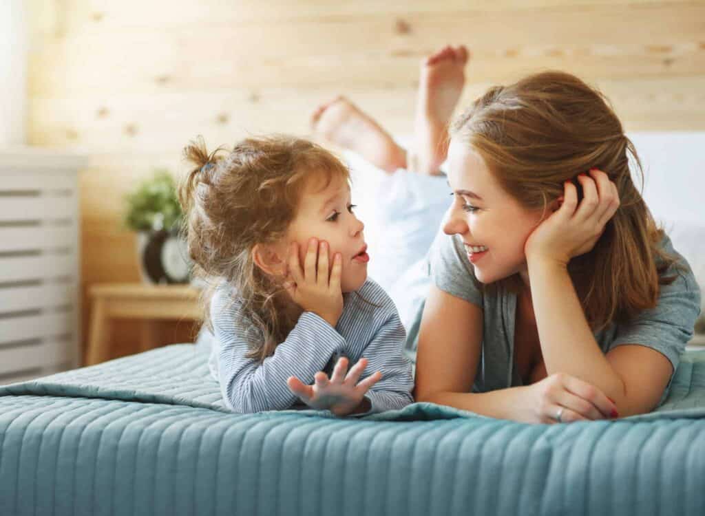 A smiling woman and young girl enjoy a cozy conversation together on their bed in a warmly lit bedroom, reflecting the peace of mind that comes with Bell Brothers' trusted service. Our No Surprise Guarantee, background-checked technicians, and upfront pricing have earned us a strong reputation in communities across Northern California.