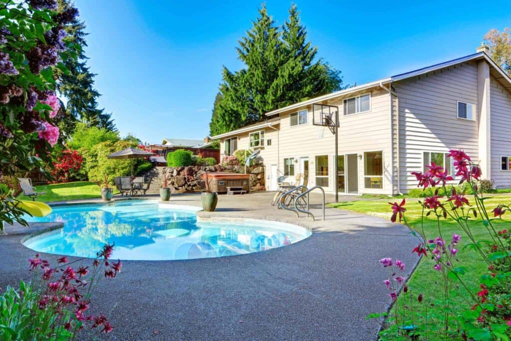 A beautifully landscaped backyard featuring a round swimming pool and comfortable lounge chairs beside a spacious two-story beige home with large windows. Bell Brothers is proud to serve Northern California communities, offering our trusted No Surprise Guarantee, fully background-checked technicians, and honest upfront pricing for your peace of mind.
