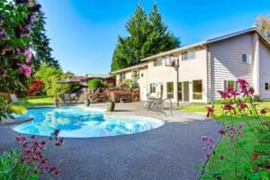 A beautifully landscaped backyard featuring a round swimming pool and comfortable lounge chairs beside a spacious two-story beige home with large windows. Bell Brothers is proud to serve Northern California communities, offering our trusted No Surprise Guarantee, fully background-checked technicians, and honest upfront pricing for your peace of mind.