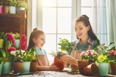 A smiling adult and child, both wearing aprons, enjoy potting plants together at a table filled with vibrant flowers and greenery. Just like this scene of care and teamwork, Bell Brothers brings trusted service to Northern California families—with background-checked technicians, honest upfront pricing, and our No Surprise Guarantee. It’s no wonder so many communities count on us for friendly expertise they can depend on.