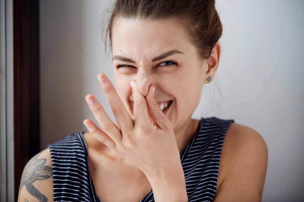 A woman in a striped tank top smiles while covering her nose, playfully squinting one eye—reminding customers that with Bell Brothers’ trusted No Surprise Guarantee, background-checked technicians, and honest, upfront pricing, families across Northern California can breathe easy and feel confident in our outstanding service.