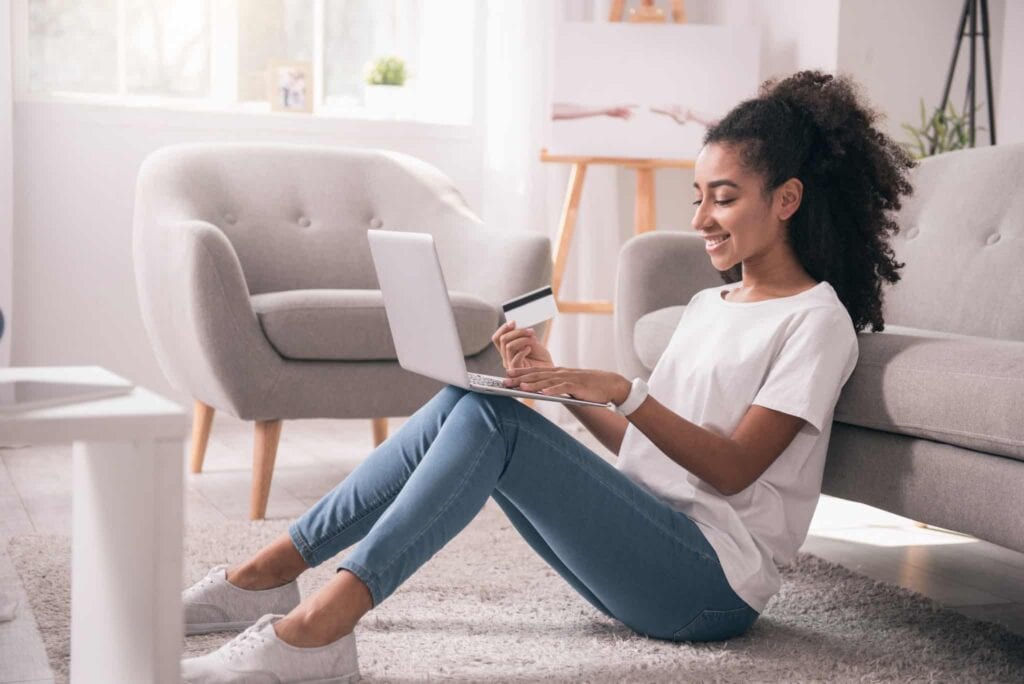 A woman sits comfortably on her living room floor, using her laptop and credit card to conveniently schedule trusted service with Bell Brothers. She enjoys peace of mind knowing she's backed by Bell Brothers’ No Surprise Guarantee, background-checked technicians, upfront pricing, and the company’s outstanding reputation in Northern California communities.