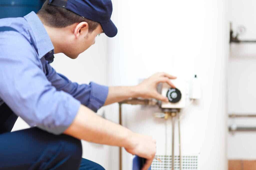 A Bell Brothers technician, dressed in a blue uniform and cap, expertly adjusts the control panel of a water heater. Our background-checked professionals proudly serve Northern California communities with our trusted No Surprise Guarantee and clear, upfront pricing—delivering reliable service you can always count on.