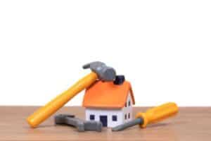 A small model house sits on a wooden surface, topped with a hammer, screwdriver, and wrench—symbolizing the expert home services Bell Brothers proudly provides. With our No Surprise Guarantee, thoroughly background-checked technicians, and honest upfront pricing, it’s easy to see why Northern California communities trust Bell Brothers for reliable heating, cooling, and plumbing care.