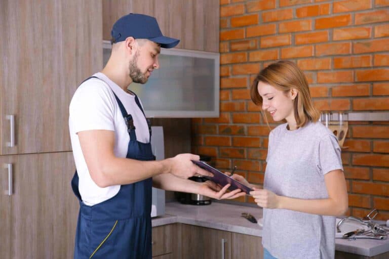 A Bell Brothers technician, easily identified by his professional uniform and friendly demeanor, stands in a beautiful kitchen with brick and wood finishes. He hands a clipboard to a smiling customer, who’s ready to sign with confidence—knowing she’s protected by our No Surprise Guarantee. Every Bell Brothers technician is thoroughly background-checked, and we offer honest, upfront pricing. Families across Northern California trust us for dependable service and peace of mind in their homes.