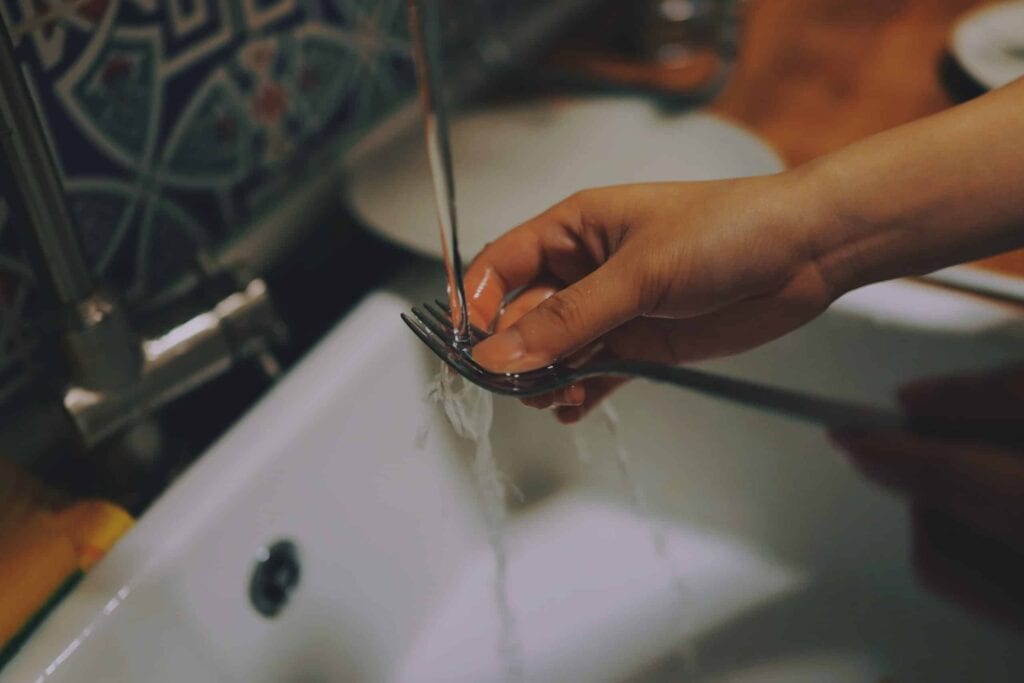 A friendly Bell Brothers technician washes a fork under running water in a clean kitchen sink, showcasing the team’s commitment to professionalism and care. With our No Surprise Guarantee, background-checked technicians, and clear upfront pricing, homeowners across Northern California rely on Bell Brothers for trusted service with every visit.