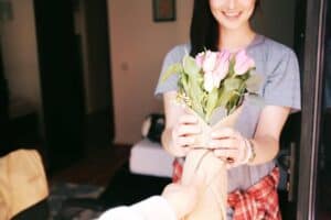 A trusted Bell Brothers technician, known for their background checks and professionalism, greets a smiling Northern California homeowner at her door with a bouquet of pink tulips. This scene reflects Bell Brothers’ No Surprise Guarantee, upfront pricing, and the genuine care that has earned them a strong reputation in communities across Northern California.