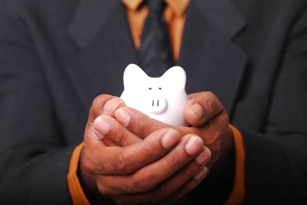 A person in a suit gently holds a white piggy bank, representing the financial peace of mind that Bell Brothers provides. Through our No Surprise Guarantee, background-checked technicians, and honest, upfront pricing, we deliver trusted service to families across Northern California communities.