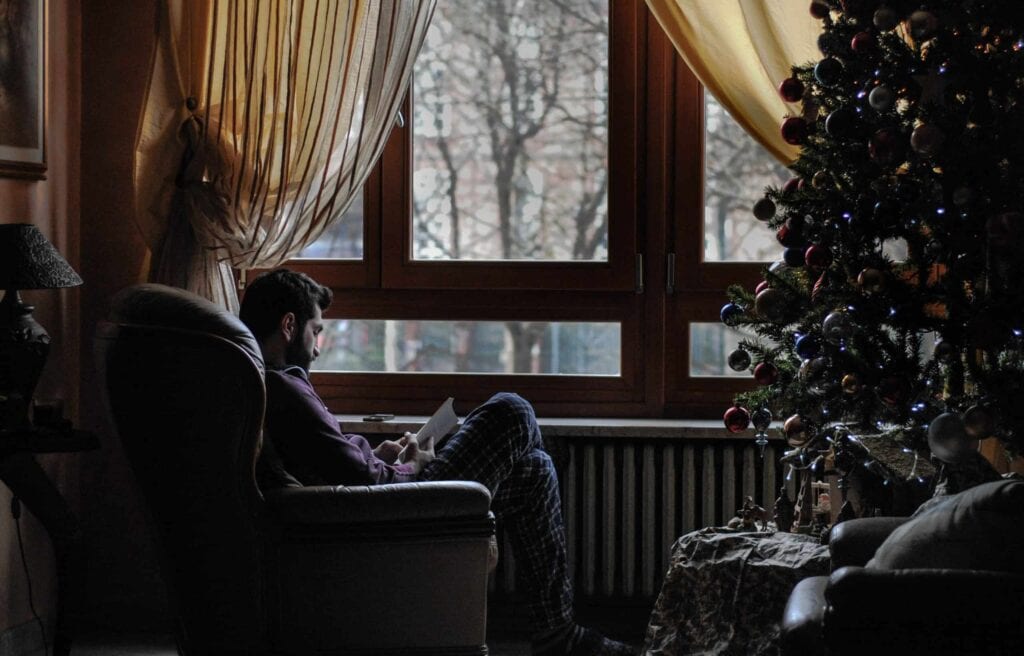 A cozy living room scene shows a person relaxing in an armchair by the window, enjoying a good book beside a beautifully decorated Christmas tree. With warm lighting and elegant curtains, this inviting space reflects the comfort and peace of mind Bell Brothers brings to homes across Northern California. Our trusted, background-checked technicians, upfront pricing, and No Surprise Guarantee ensure you can relax knowing your home is in expert hands.