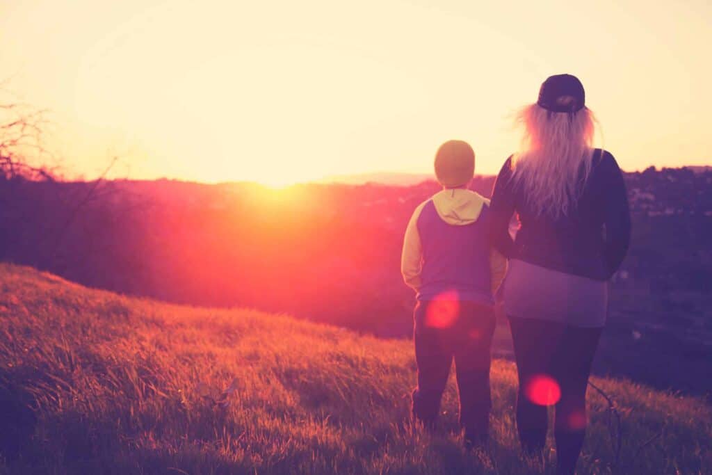 Two people stand on a sunlit grassy hill at sunset, looking toward the horizon. The scene is bright and inviting, capturing the warm glow of the setting sun—symbolic of Bell Brothers’ No Surprise Guarantee and our commitment to honest, upfront pricing. Just as you can trust in a beautiful day’s end, you can count on our background-checked technicians and stellar reputation for dependable service across Northern California communities.