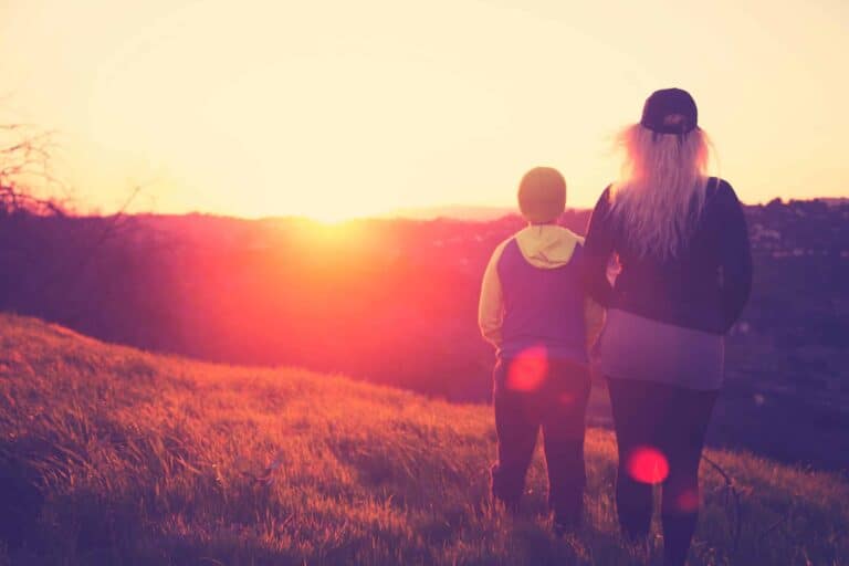 Two people stand on a sunlit grassy hill at sunset, looking toward the horizon. The scene is bright and inviting, capturing the warm glow of the setting sun—symbolic of Bell Brothers’ No Surprise Guarantee and our commitment to honest, upfront pricing. Just as you can trust in a beautiful day’s end, you can count on our background-checked technicians and stellar reputation for dependable service across Northern California communities.