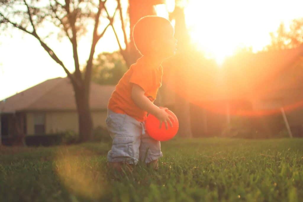 A young child holding an orange ball enjoys playing in a sunlit yard at sunset, with warm rays shining through trees and homes nearby. At Bell Brothers, we’re dedicated to creating safe, comfortable spaces for families just like yours—backed by our No Surprise Guarantee, trusted background-checked technicians, and honest upfront pricing. Proudly serving Northern California communities with a reputation you can count on.