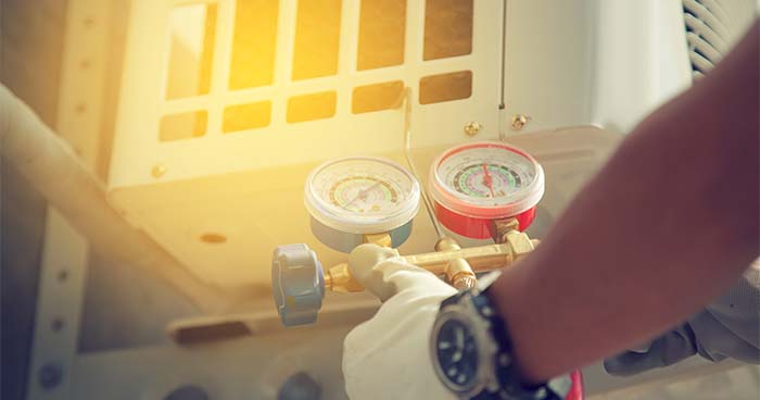 Image: an HVAC technician measures refrigerant levels.