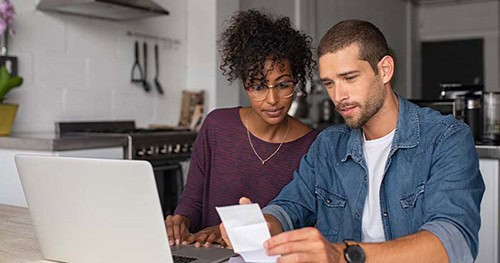 Image: a couple sits together and goes over their monthly bills.