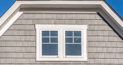 Single hung windows on the second-story of a brown house.