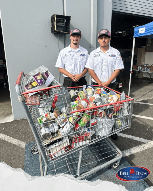 Two Bell Brothers technicians, background-checked and uniformed, support the community with canned goods—No Surprise Guarantee shown.