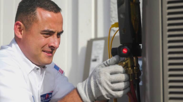 A trusted, background-checked Bell Brothers technician tunes an outdoor HVAC unit, backed by our No Surprise Guarantee and upfront pricing.